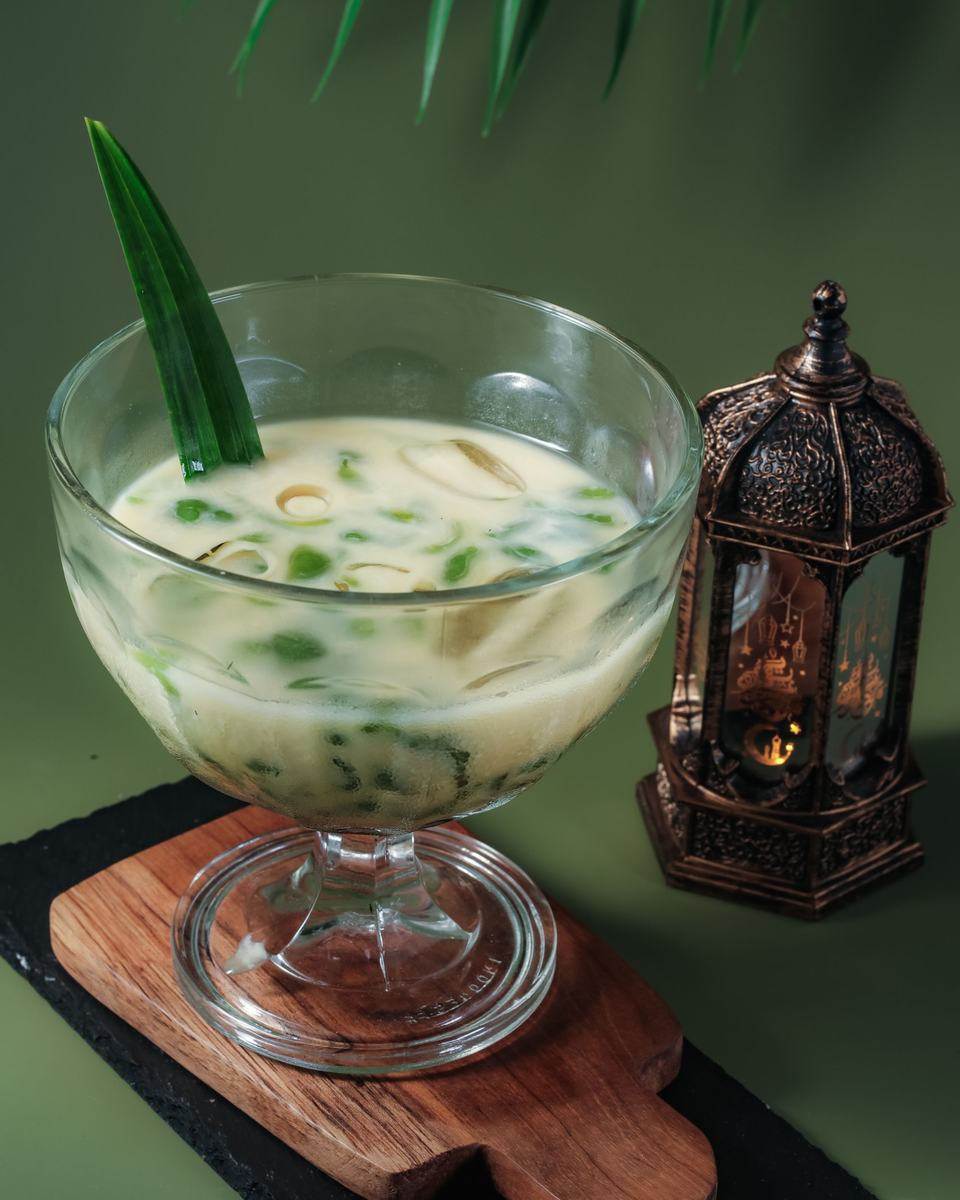 A glass of chendol with green pandan jelly in coconut milk.