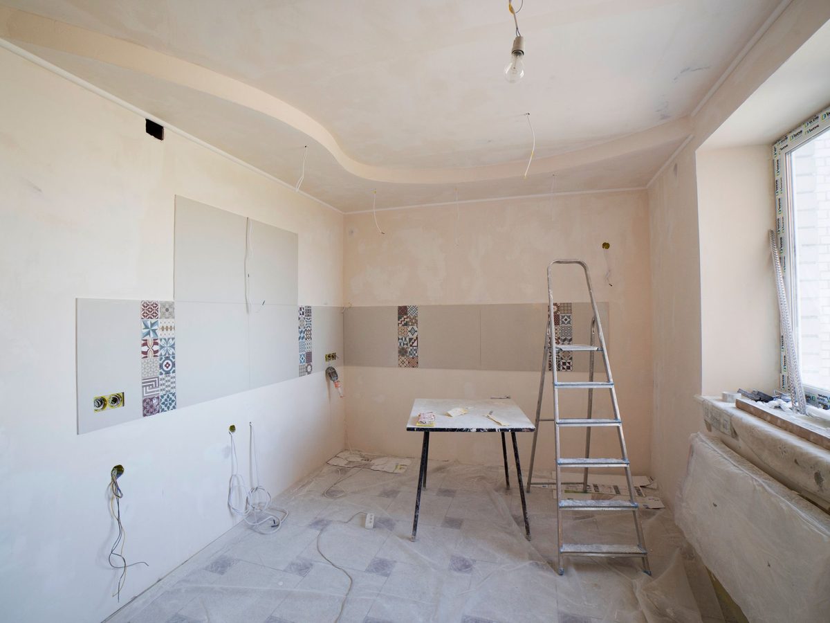 Before: a stripped kitchen with bare plastered walls, a ladder and a protected floor.
